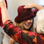 Jill Snow (left) tries on handmade hats with the help of Annie Ross during the &ldquo;Boost Betty into the Building Fund&rdquo; Art Attack auction and jumble sale on Nov. 5 at the Everett Unity Center for Positive Living. (Kevin Clark / The Herald)