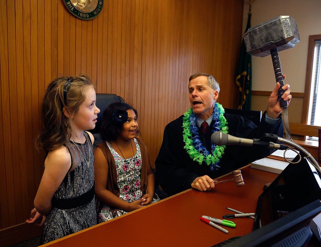 After finalizing their adoptions by Nick and Erin Schramm, Superior Court Judge, David A. Kurtz offers Kortnei, 9, and Miah, 8, a choice between striking the desk with a standard gavel or a super-sized gavel. Both went for the big silver one. (Dan Bates / The Herald)