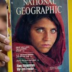 In this file photo taken Oct. 26, the owner of a book shop shows a copy of a magazine with the photograph of Afghan refugee woman Sharbat Gulla, from his rare collection in Islamabad, Pakistan. (AP Photo/B.K. Bangash, File)