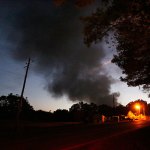 Light from a light pole shows a house near a plume of smoke from a Colonial Pipeline explosion, on Monday, Oct. 31, in Helena, Alabama. Colonial Pipeline said in a statement that it has shut down its main pipeline in Alabama after the explosion in a rural part of the state outside Birmingham. (AP Photo/Brynn Anderson)