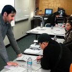 Kamal Acharya, who came from Bhutan and speaks Nepali, helps a voter understand the ballot. (Julie Muhlstein / The Herald)