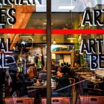 In a cozy atmosphere, partially visible through painted signs and street reflections on the front window panes, Janet Hada (left front table) and her sister, Susan Hada, who work for the U.S. Forest Service in Everett, enjoy coffee Tuesday morning at Cafe Zippy on Wetmore Avenue, where they are regular customers. Rich Horton works on his computer at a table off to the right. Marilyn Rosenberg, owner (in green apron, back), is preparing to move the restaurant/coffee-house from 2811 Wetmore Ave. to the former home of Under the Red Umbrella. That cafe, at 1502 Rucker Ave. in north Everett, closed in 2015. (Dan Bates / The Herald)