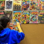 Angie Wang hangs comic books during the Sno-Isle ComicCon Sunday morning at the Snohomish Library. (Kevin Clark / The Herald)
