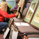 Glenda Smith browses the artwork during the event. (Kevin Clark / The Herald)