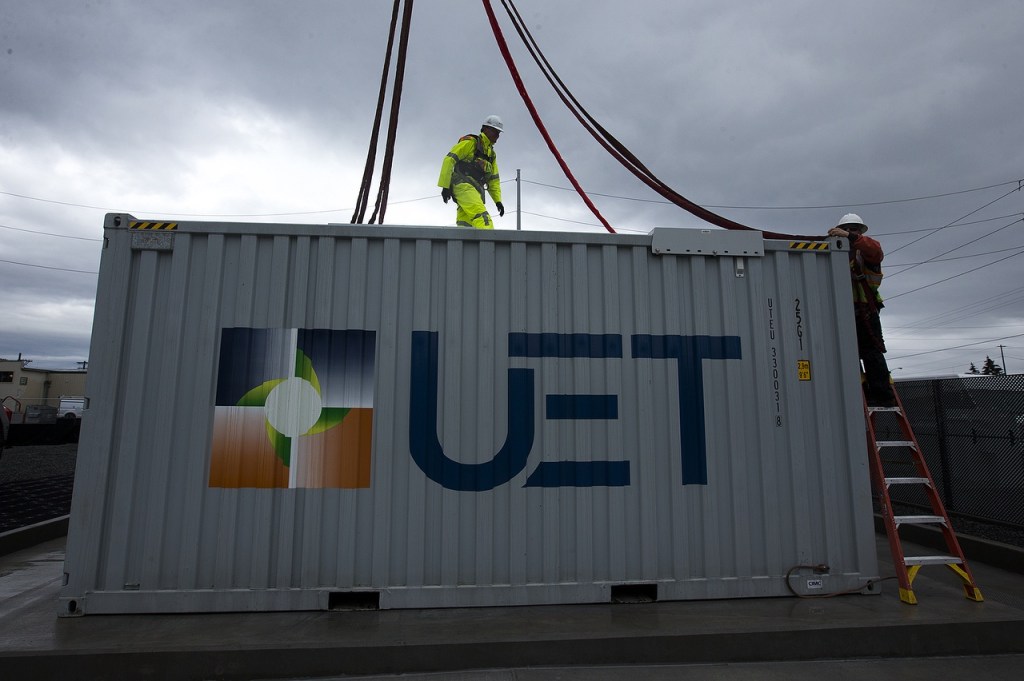 PUD workers unclip fasteners from a crane after placing a vanadium flow battery in place at the Everett Substation. The twenty newly installed batteries are scheduled to go live in March. (Ian Terry / The Herald)