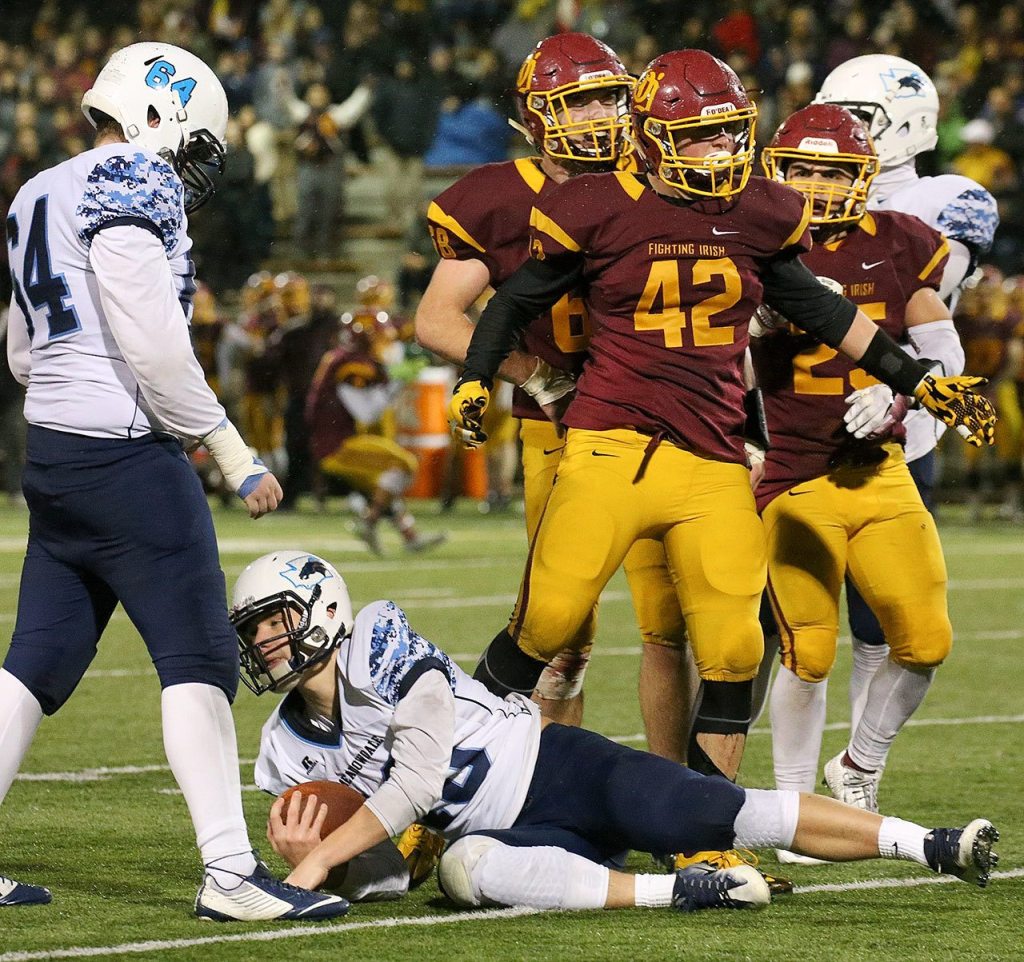 O&rsquo;Dea&rsquo;s Kyle Hollabaugh (42) celebrates a sack of Meadowdale&rsquo;s Drew Tingstad with Meadowdale&rsquo;s Bryce Chapman looking on during a 3A state semifinal game Saturday at Pop Keeney Stadium in Bothell. O&rsquo;Dea won 35-9. (Kevin Clark / The Herald)