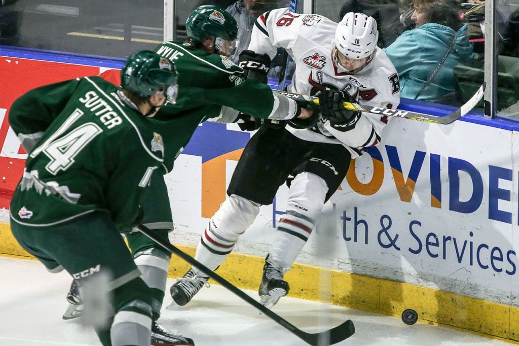 Everett&rsquo;s Wyatte Wylie checks Red Deer&rsquo;s Grayson Pawlenchuk with Everett&rsquo;s Riley Sutter closing during a game Wednesday night at Xfinity Arena in Everett. (Kevin Clark / The Herald)