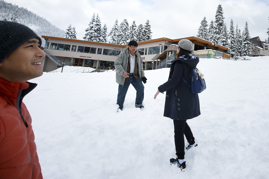 Phong Truong (left), of Seattle, takes in the view at Stevens Pass while his aunt and uncle snap photos during a visit on Thursday. Truong&rsquo;s family is visiting from Vietnam and had never touched snow until their Thursday excursion to the mountains. (Ian Terry / The Herald)