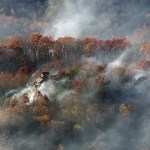 Smoke surrounds a home as seen from aboard a National Guard helicopter near Gatlinburg, Tennessee, on Tuesday, Nov. 29. (AP Photo/Erik Schelzig)