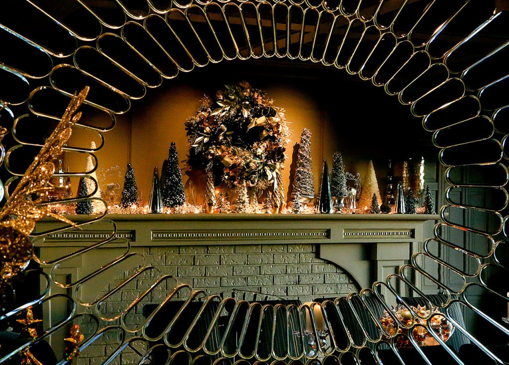 The dining room fireplace mantle, adorned in the season by Larry and Linda Jubie, is reflected in a large ornate mirror at the opposite side of the room. (Dan Bates / The Herald)
