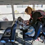 Jessiana King buckles her son, Brayden Varnes, into a car seat aboard the baby bus after school at Crossroads High in Granite Falls. Currently, King is the only student on the bus for the 7-minute ride home. (Kevin Clark / The Herald)