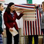 A poll worker lifts the curtain as Sen. Kelly Ayotte, R-N.H., center, leaves the voting booth with her daughter, Kate, on Tuesday, Nov. 8, at Charlotte Avenue Elementary School in Nashua, New Hampshire. (AP Photo/Elise Amendola)
