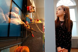 Darby Kelly, 7, niece of the Edmonds Historical Museum Director, Caitlin Kelly, explores display cases filled with very old play things that make up the current holiday exhibit &ldquo;Once Upon a Toy.&rdquo; (Dan Bates / The Herald)