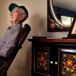 Raymond Lund, 95, a World War II veteran who served in Europe, including landing on the beach at Normandy on D-Day, sits in a rocker at his home in Stanwood. A framed photograph of his wife, Aileen sits on a cabinet behind him with a lei hanging over it. Aileen, who died last year, and Ray were married for 65 years. (Dan Bates / The Herald)