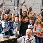 Kiwanis Club volunteers Jack Lapoint (center floor) and James Henry (right) pose with third-graders for teacher Christi Castro to photograph after giving the kids new dictionaries from the Kiwanis Club for the last time. (Dan Bates / The Herald)