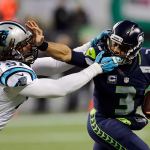 Seahawks quarterback Russell Wilson (3) stiff-arms the Panthers&rsquo; Ryan Delaire as he runs with the ball in the first half of a game Dec. 4 in Seattle. (AP Photo/Stephen Brashear)