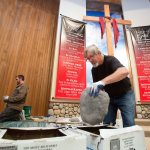 Mason Chuck Hein, of Chuck&rsquo;s Masonry, picks through boxes of river rock to find the right piece for lining the baptistry at Calvary Baptist Church on Colby in Everett on Wednesday as his son, Harley, works along with him. (Andy Bronson / The Herald)