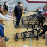 Ricki Davis, left, and Katie Helmke and Alex Cizek, right, try to pull apart two stuck shopping carts as students, alumni and volunteers gather and deliver food from Cascade High School on Wednesday, Dec. 14, 2016 in Everett, Wa. (Andy Bronson / The Herald)