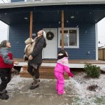 With her infant son, Matias, on her chest, Sandy Flores enjoys falling snow Saturday with her son, Ray J., and daughter, Sasha, in front of their new home in Everett. Flores, her husband, Ray, and their three young kids became the new owners of Phoenix II, a house in North Everett from Habitat for Humanity of Snohomish County. They contributed more than 500 hours of sweat equity in the construction of the home. (Andy Bronson / The Herald)