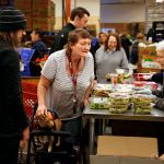 Assisted by volunteers, Adam Szydel (left) and Marge Beauchamp (right), Kerrin Thompson, of Marysville, picks out a few items at the Marysville Food Bank, just days before Thanksgiving. Thompson was also able to get something for her small service dog, Diego. (Dan Bates / The Herald)