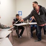 Classmates clap as Jake Marsh hands seventh-grader Adrian Seeker his personal copy of the book &ldquo;A Hand to Guide Me,&rdquo; written by Denzel Washington about mentors, after the group graduated from the &ldquo;Passport to Manhood&rdquo; program at Voyager Middle School in Everett on Tuesday. (Andy Bronson / The Herald)