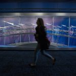 As a call to line up for the Boeing Assembly plant is made, a tourist runs past a display of Boeing airplanes at the Future of Flight Museum on Dec. 8 in Everett. (Andy Bronson / The Herald)