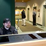 Security guard Shawn Nordby watches the front door as another guard escorts a visitor up the elevators in the Wall Street building on Monday in Everett. A new set of guidelines gives a uniformed security guard the power to turn visitors away from the Wall Street building, which houses the offices of Mayor Ray Stephanson and other city departments. (Andy Bronson / The Herald)