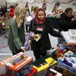 Nibras Fakhri (center), of Everett, picks out presents for her children with the help of volunteer Stephanie Myers (left) at the annual Christmas House holiday gift giveaway in Everett on Friday, Dec. 2. (Ian Terry / The Herald)