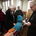 Pastor Wayne Bond (right) looks over shawls handmade by the Trinity Episcopal knit and crochet group including members Barbara Linvog (center left) and Brenda Congdon (left) at the Everett church Nov. 29. (Ian Terry / The Herald)