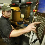 Machinist David Willis makes adjustments to a CNC machine at RB Enterprises in Mukilteo on Wednesday. (Ian Terry / The Herald)
