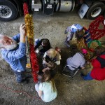 On Nov. 15, Chuck Donaldson (left), of Sultan, and other volunteers work to switch old lightbulbs with new LED&rsquo;s on Sultan&rsquo;s Christmas train that currently hangs on the awning at City Hall. (Ian Terry / The Herald)