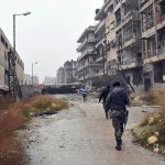 This photo, released by the Syrian official news agency SANA, shows Syrian troops and pro-government gunmen marching through the streets of east Aleppo, Syria, on Tuesday. (SANA via AP)