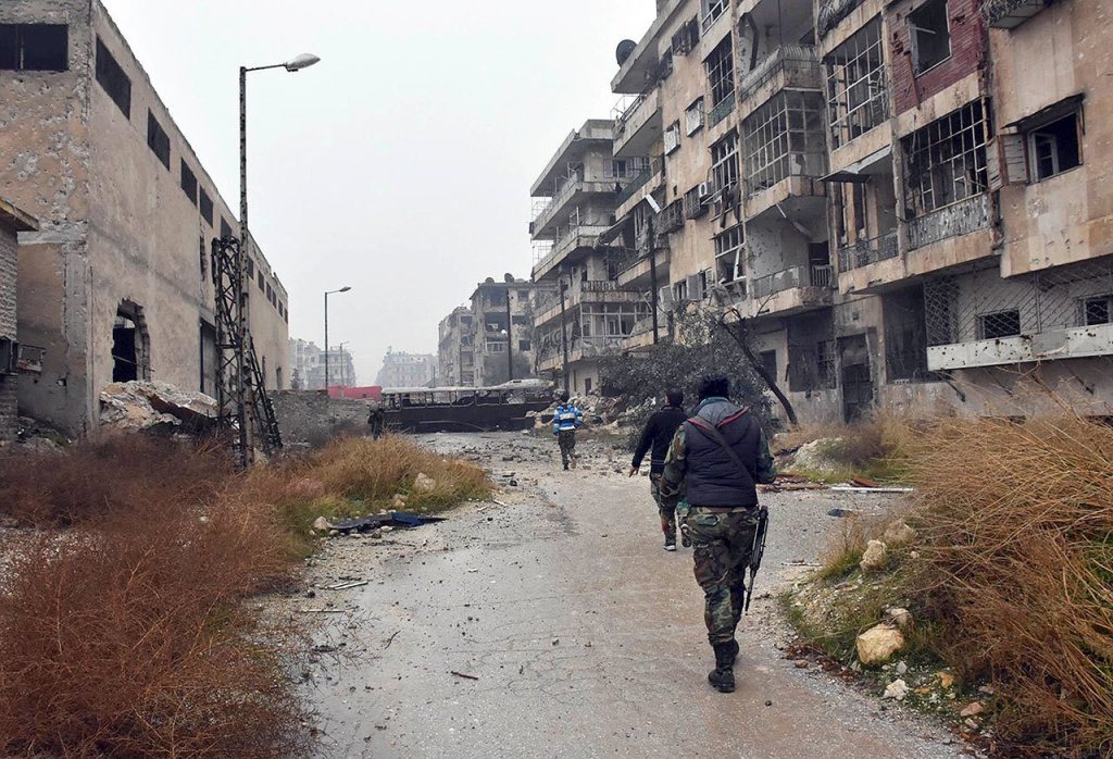 This photo, released by the Syrian official news agency SANA, shows Syrian troops and pro-government gunmen marching through the streets of east Aleppo, Syria, on Tuesday. (SANA via AP)