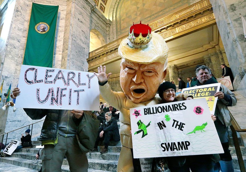 Jo Walter of Bremerton wears a large Donald Trump head to protest Electoral College voting on Monday at the Capitol in Olympia, where Washington members met to cast their votes. (AP Photo/Elaine Thompson)