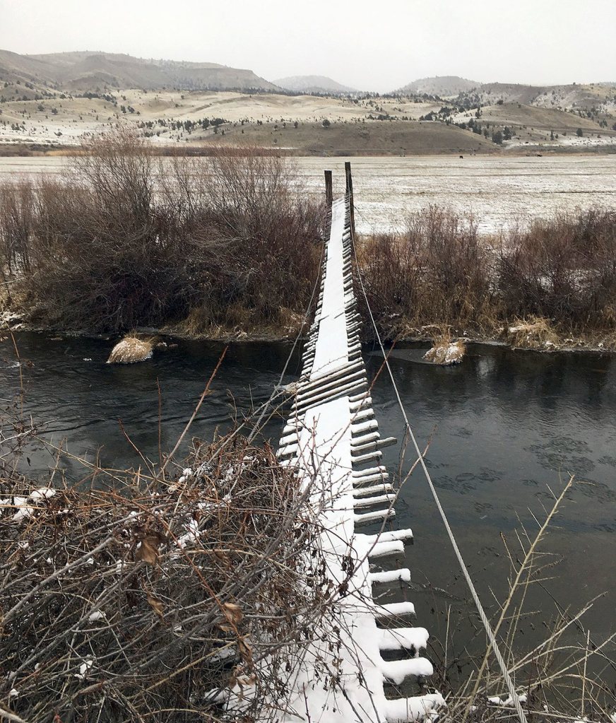 In this Dec. 8, 2016 photo, a worn footbridge crosses the John Day River and is dusted by newly fallen snow near Dayville. (AP Photo/Andrew Selsky)