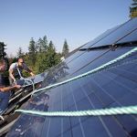 Guy Knoblich (left) and Kevin Bell lift a solar panel into its place in a 16-panel array on the roof of a Camano Island home in 2012. Everett City Councilman Paul Roberts is leading an effort to help grow the &ldquo;green&rdquo; economy in Washington. One of the first steps is assessing what&rsquo;s being done in the state. (Herald file)
