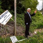 Mohammed Riaz Khan waves at a passerby he knows near the intersection of Harbour Point Blvd. and Mukilteo Speedway, while visiting the site of the planned mosque, The Islamic Center of Mukilteo, in early May. The signage, which had fallen or was blown down, is at the east end of the property. (Dan Bates / Herald file)