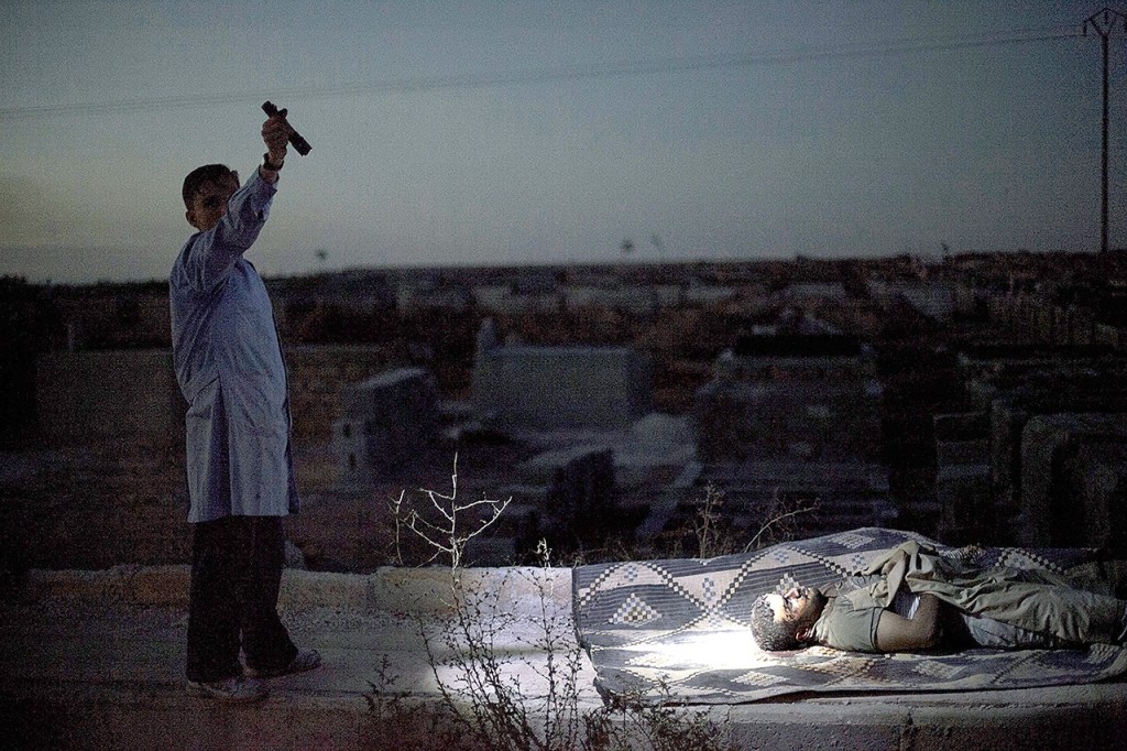 A man points a flashlight towards the body of a Syrian man killed by Syrian army shelling at a graveyard in Aleppo, Syria, on Oct. 13, 2012. (AP Photo/Manu Brabo, File)