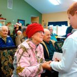 St. Michael Catholic School student Ian Benningfield presents a card to a resident of Pacifica Senior Living in Snohomish during a recent visit. (Contributed photo)