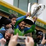 Sounders player Roman Torres holds the MLS Cup trophy as the team begins a parade through downtown Seattle on Tuesday. Seattle beat Toronto FC 5-4 in a penalty kick shootout Saturday to win its first MLS championship. (AP Photo/Elaine Thompson)