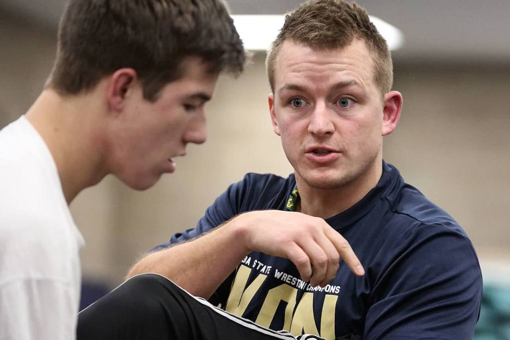 New Arlington wrestling coach Jonny Gilbertson demonstrates on Will Rush during practice Wednesday. (Kevin Clark/The Herald)