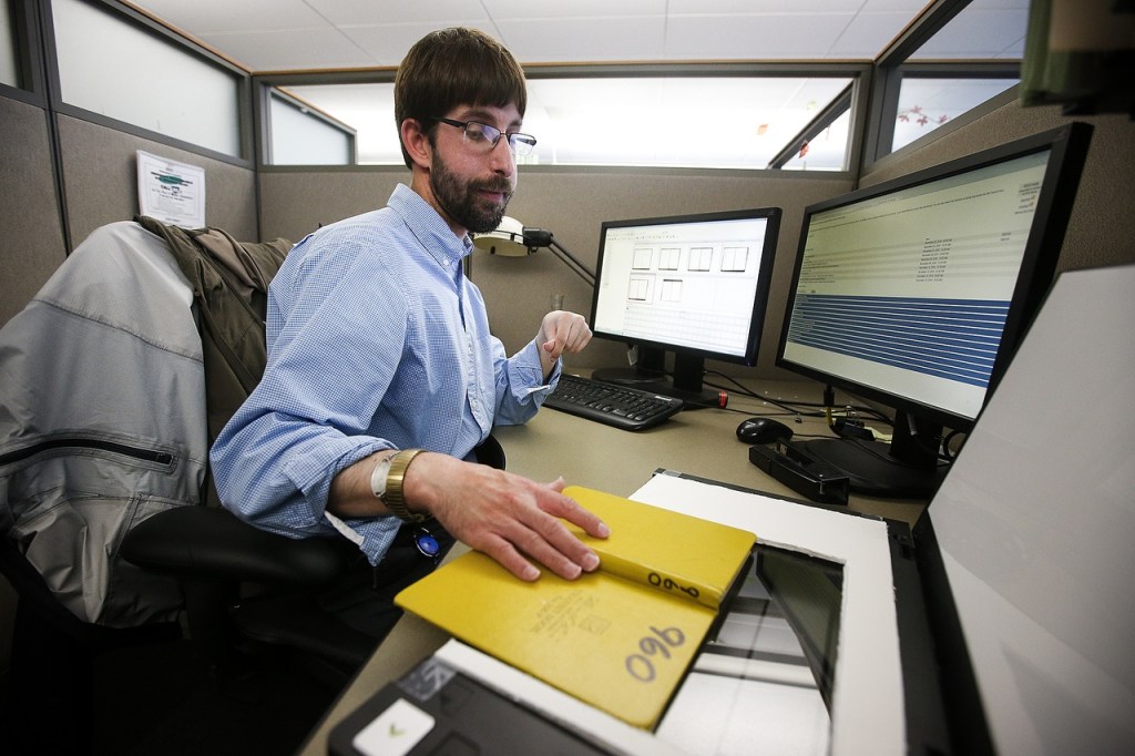 James Oliver scans field books with notes taken by Snohomish county workers at his desk in Everett on Nov. 2. Oliver spends much of his day meticulously archiving historic copies of the field books, which date back to the late 1800s. (Ian Terry / The Herald)