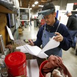 Heng Hun looks through notes while working at RB Enterprises in Mukilteo on Wednesday. Hun has worked at RB Enterprises for five years and has been a machinist for almost 15 years. (Ian Terry / The Herald)