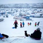 The Oceti Sakowin camp where people have gathered to protest the Dakota Access oil pipeline stands in the background as a children sled down a hill in Cannon Ball, North Dakota, on Thursday, Dec. 1. (AP Photo/David Goldman)