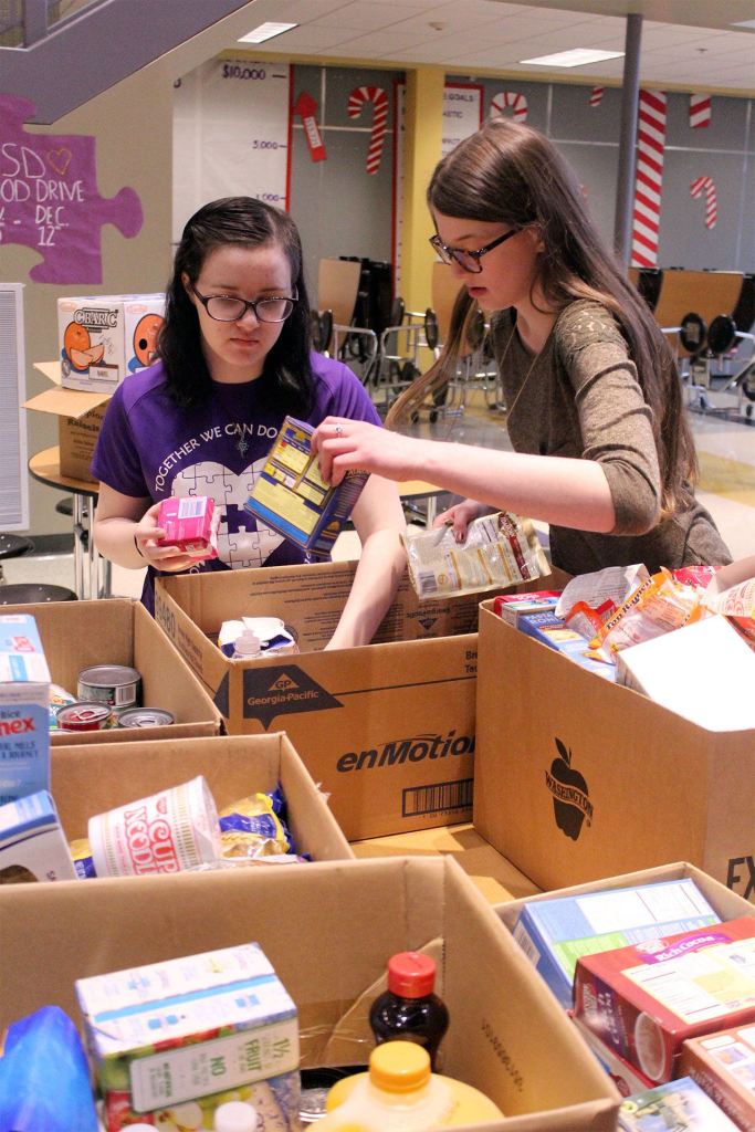 Food Drive Coordinator Isabella Hensley receives help from student Breanna Wilkerson while packing food boxes for local families. (Contributed photo)