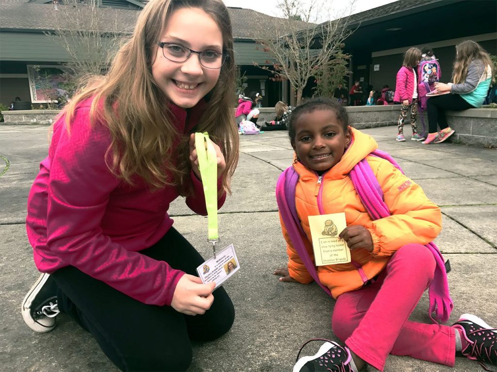 Izabel Negron (right) is helped by Shoelace Brigade member Makenzie Powers at Penny Creek Elementary School. (Contributed photo)