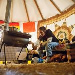 In this Tuesday, Nov. 29 photo, Grandma Redfeather of the Sioux Native American tribe sits by the wood stove in her yurt at the Oceti Sakowin camp where people have gathered to protest the Dakota Access oil pipeline in Cannon Ball, North Dakota. &ldquo;I&rsquo;m sitting here in my prayer&rdquo; said Redfeather of living at the camp since July. &ldquo;I&rsquo;ll stand on my treaty and fight.&rdquo; (AP Photo/David Goldman)