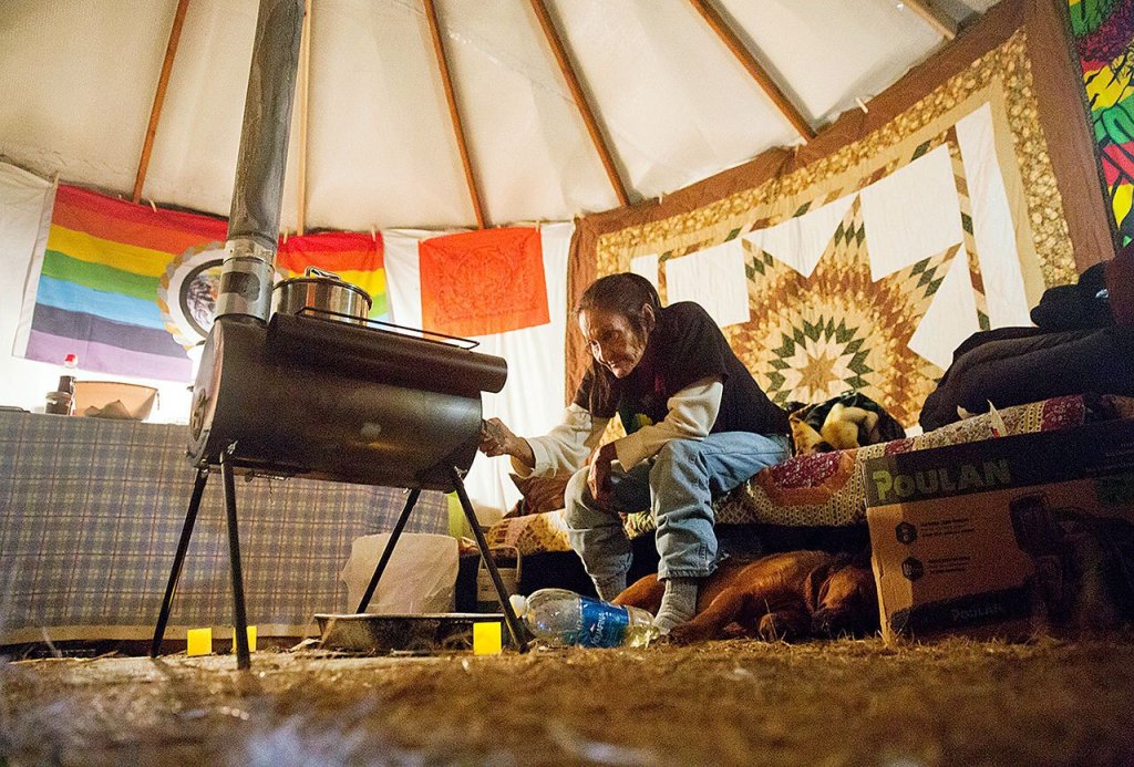 In this Tuesday, Nov. 29 photo, Grandma Redfeather of the Sioux Native American tribe sits by the wood stove in her yurt at the Oceti Sakowin camp where people have gathered to protest the Dakota Access oil pipeline in Cannon Ball, North Dakota. &ldquo;I&rsquo;m sitting here in my prayer&rdquo; said Redfeather of living at the camp since July. &ldquo;I&rsquo;ll stand on my treaty and fight.&rdquo; (AP Photo/David Goldman)