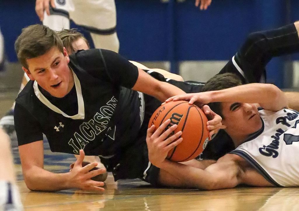 Jackson&rsquo;s Jordan Brajcich (left) and Glacier Peak&rsquo;s Bo Burns struggle for a loose ball during a game Friday at Glacier Peak High School in Snohomish. The Grizzles defeated the Timberwolves 64-41. (Kevin Clark / The Herald)