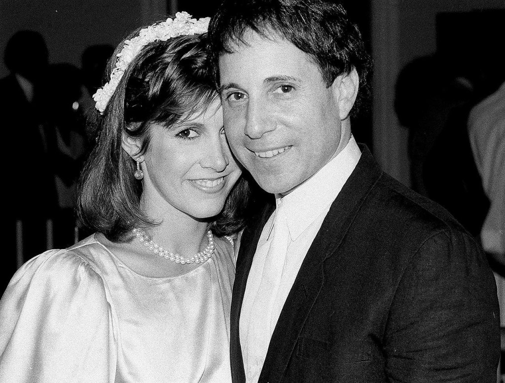 In this March 11, 1982 photo, actress Carrie Fisher and singer-composer Paul Simon leave the Cathedral of St. John the Divine in New York, after a memorial service for comedian John Belushi. (AP Photo/Marty Lederhandler, File)